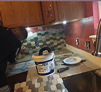 Tiles being placed onto a wall for a kitchen backsplash DIY